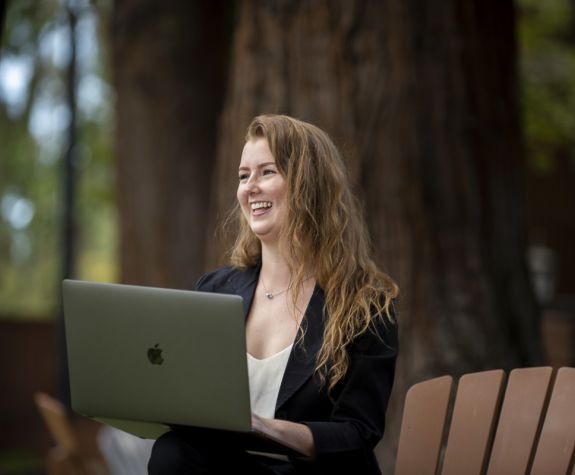 student with laptop sitting on chair outside